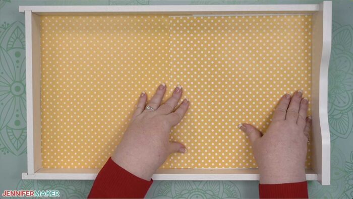 Putting pretty paper with white polka dots on a yellow background into a drawer