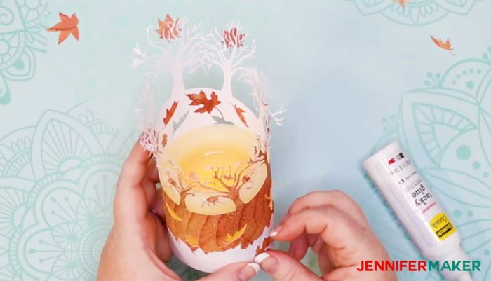 Gluing paper leaves to the base of a fall luminary candle