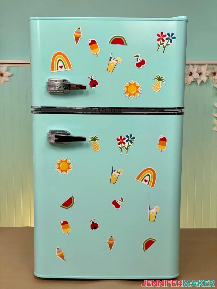 DIY fridge magnets with bright designs of fruits, summer snacks, and flowers on a retro mint refrigerator.