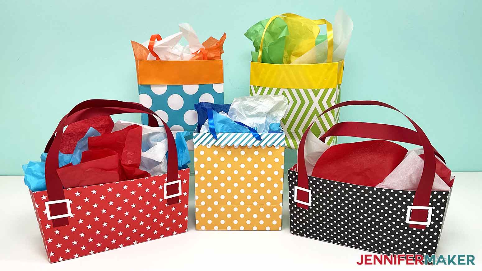 A photo showing five finished DIY gift bags with tissue paper inside. Two bags are made of wrapping paper, two are purse-shaped, and one is made of cardstock.