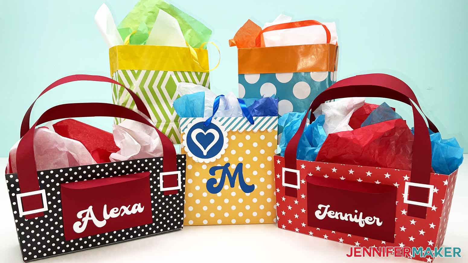A photo showing five finished DIY gift bags with tissue paper inside. Two bags are made of wrapping paper, two are purse-shaped, and one is made of cardstock with an initial and gift tag on the front.
