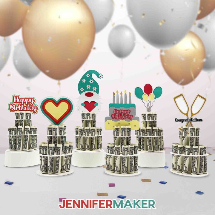 Six colorful paper money cake decorations, each holding rolled dollar bills in a column, topped with a multicolor Happy Birthday sign, a heart, a cute gnome, birthday cake, balloons, and crossed champagne flutes, made using JenniferMaker SVG files.
