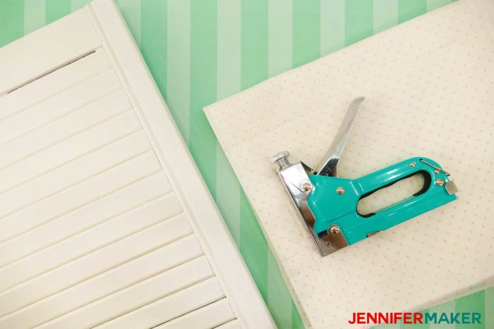 An old white shutter, material, and a staple gun are the materials you need to make a DIY Paper Organizer from a Repurposed SHutter