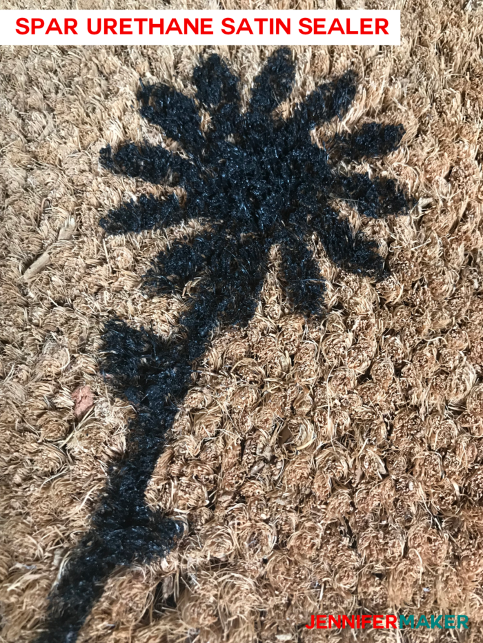 Close up of a DIY personalized door mat made of coir, painted with exterior house paint, and sealed with Spar Urethane sealer