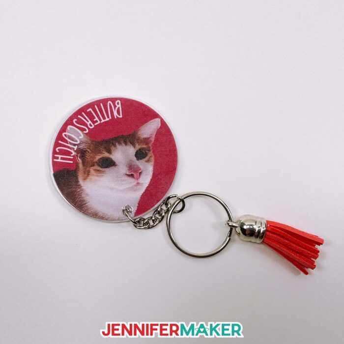 Round DIY photo keychain with a cat's image and the name Butterscotch on a red background.