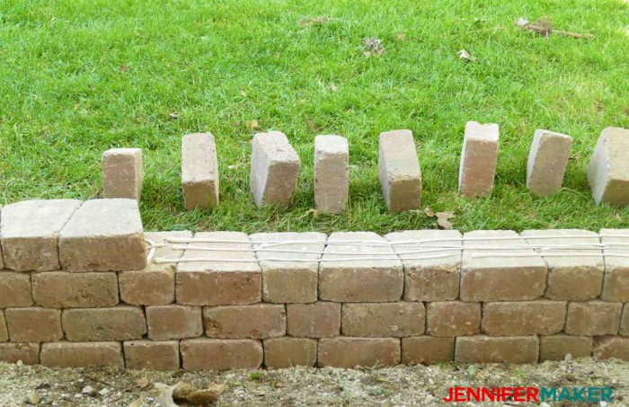 Stacking and adhesing bricks to construct a retaining wall