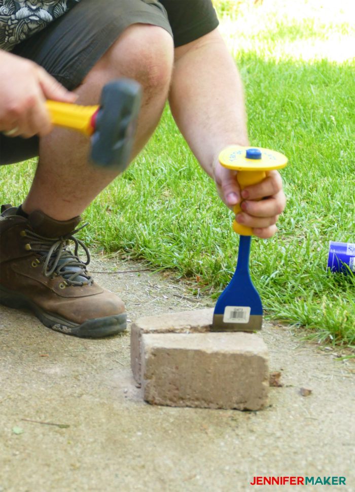 Breaking a retaining wall brick with a Mason's chisel and a hammer