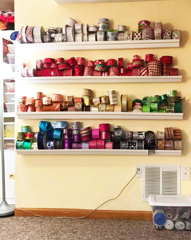 Store your ribbon spools in white rain gutters installed on a wall in a craft room for great DIY ribbon storage!