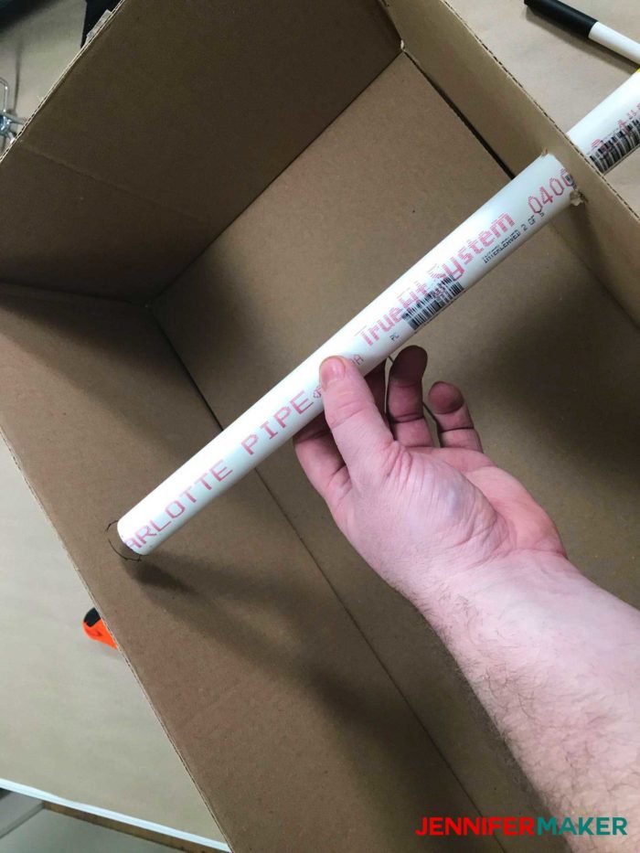Inserting the PVC pipe into the cardboard box to make the DIY tumbler turner