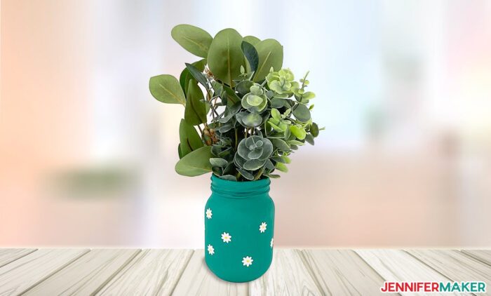 Glass jar painted in blue chalk paint with white vinyl flowers from Dollar Tree