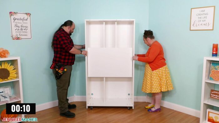 Jennifer Maker and her parter Greg Reese positioning the back cabinet of a DreamBox 2 craft storage furniture in her craft room.