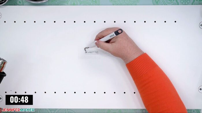 Jennifer Maker removing labels on the DreamBox 2 craft storage furniture shelves with a Cricut weeding tool.