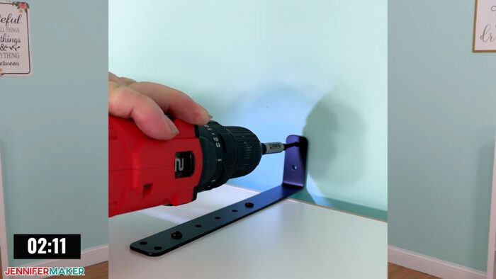 Jennifer Maker installing an included safety bracket for the DreamBox 2 craft storage solution with a power drill.