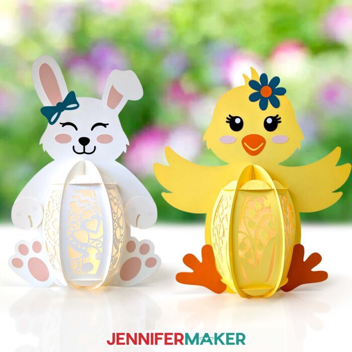 A bunny and a chick cardstock Easter Lanterns sit in an outdoor space, featuring intricate designs cut out from their bodies, through which light shines from an LED light