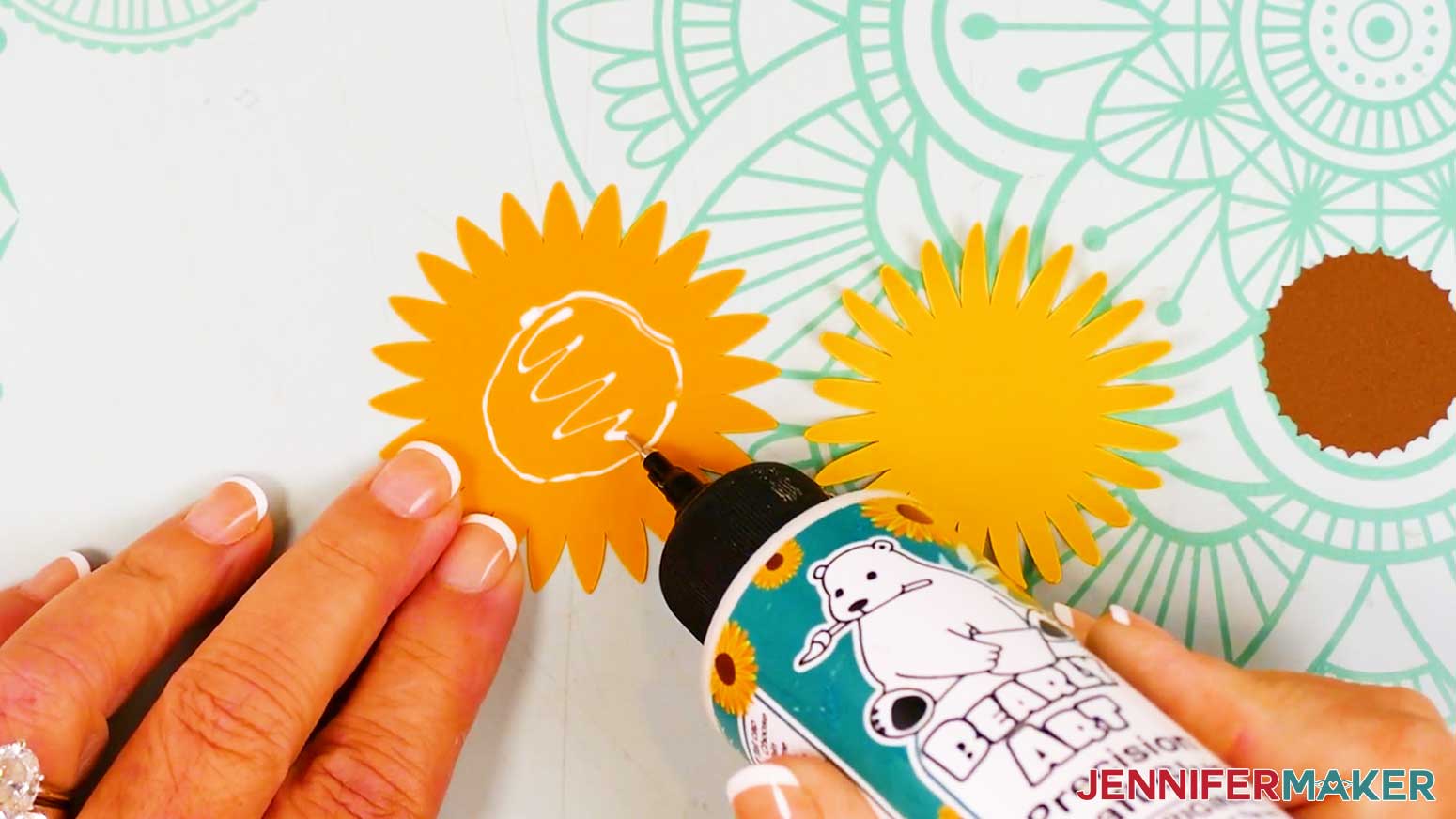 The large sunflower pieces are spread out and glue is being applied to the front of the orange bottom petals.