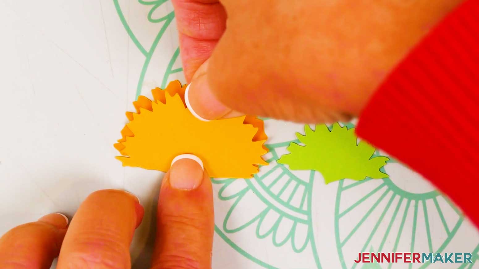 The yellow top petal layer is being glued to the bottom orange petal layer.