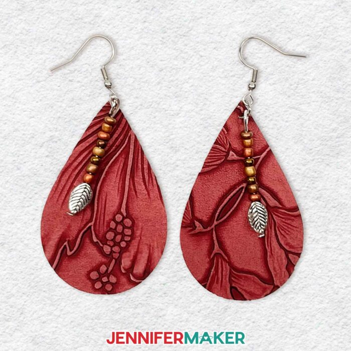 Learn to make easy DIY earrings using faux leather with JenniferMaker's tutorial! A pair of tooled faux leather earrings in a natural dark pink color with beaded leaf accents.