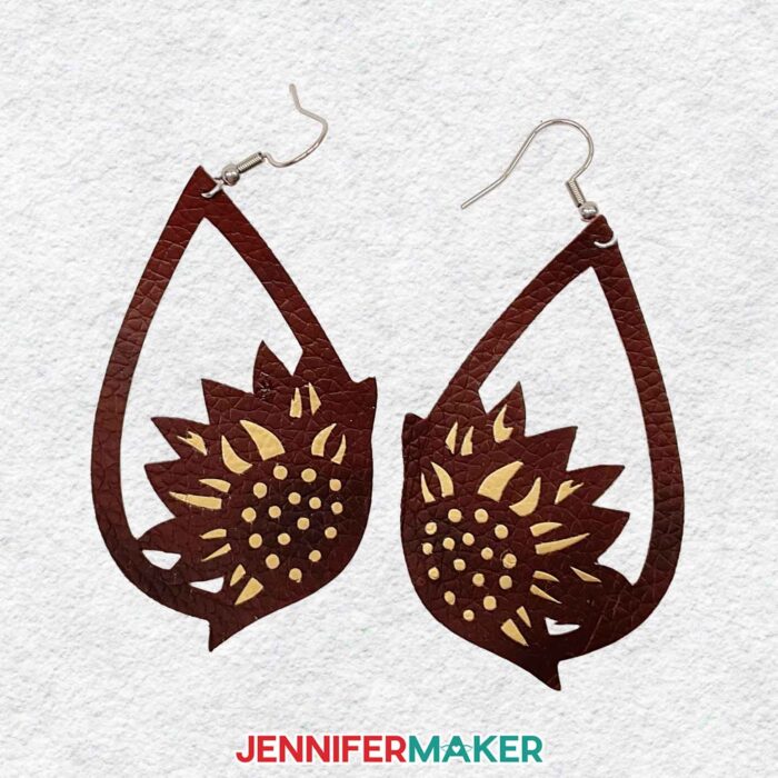 Learn to make easy DIY earrings using faux leather with JenniferMaker's tutorial! A pair of dark brown faux leather earrings with golden sunflower insets.