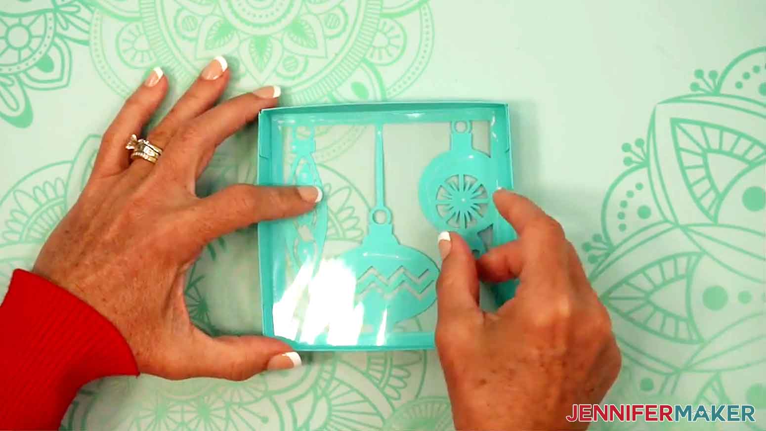 A square of acetate is being applied to the glued portion of the inside of the gift box lid.