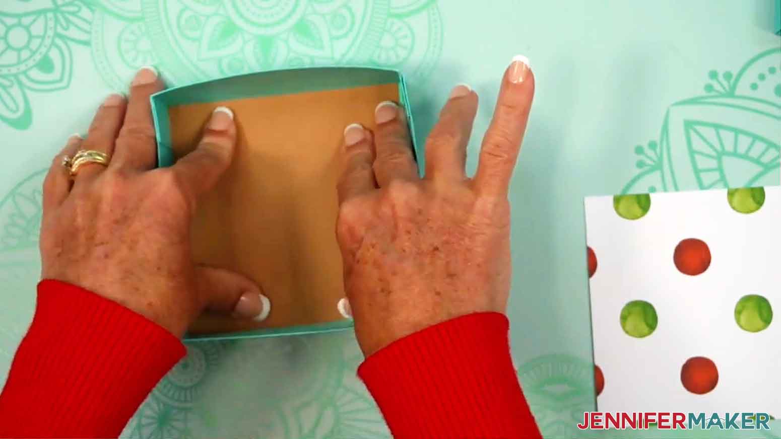 Chipboard is being glued inside the bottom of the gift box.