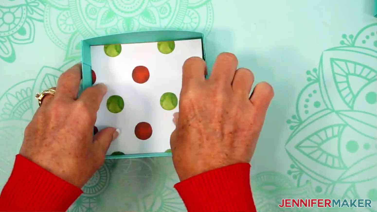 Patterned paper is being adhered on top of the chipboard in the inside of the bottom of the gift box.