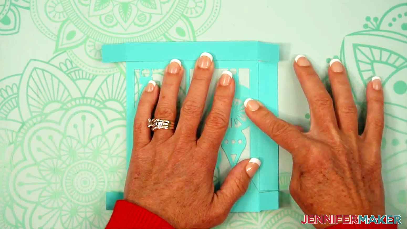 The glued side piece is being folded down towards the box lid.