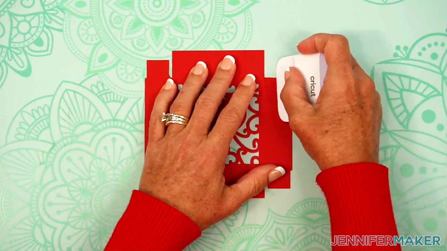 A scraper is being used to crease the corner pieces of the box lid.