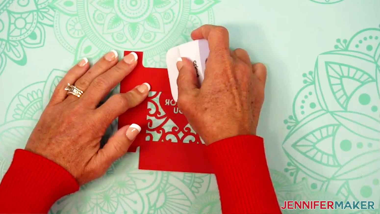 A scraper is being used to crease the side tabs of the tumbler gift box lid.