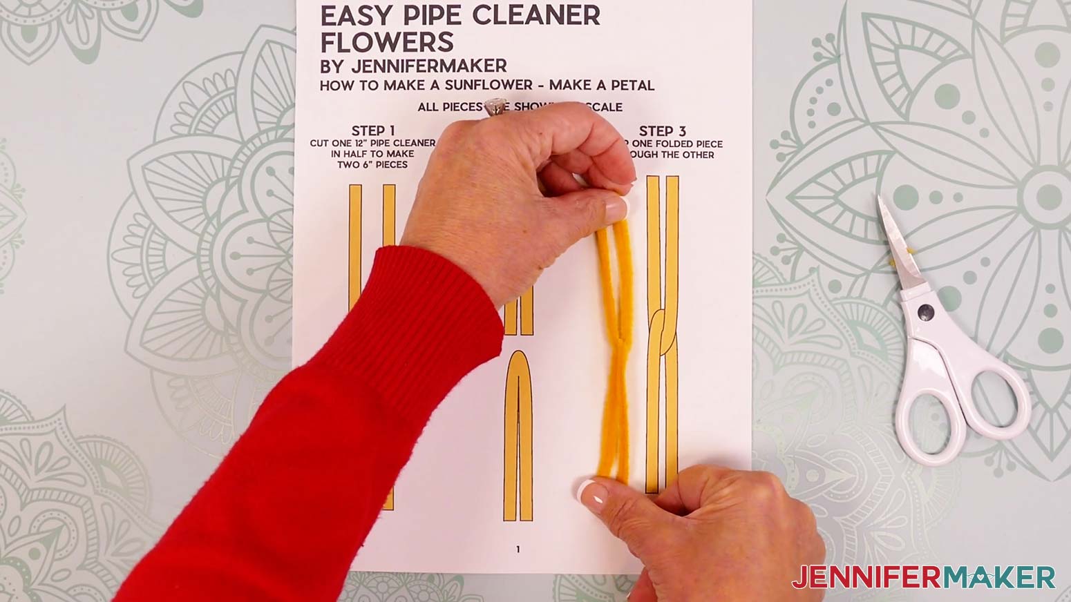 Insert the leg of one folded yellow pipe cleaner into the bend of the other so they are linked.