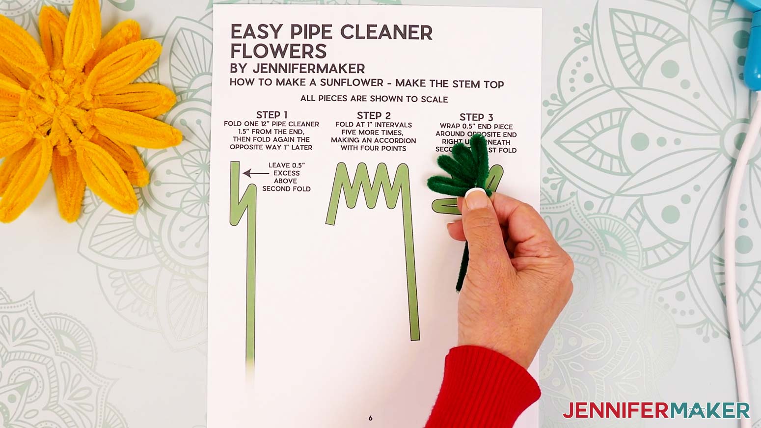 Bring the short pipe cleaner end perpendicular across the long section to create an enclosed shape with four pointed leaves.