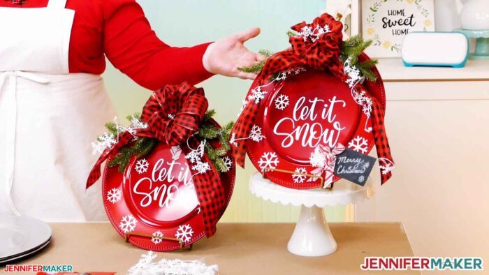 Two red charger round door signs with white vinyl and greenery and bows.