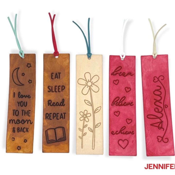 Engraved leather bookmarks with quotes and floral designs on stained backgrounds.