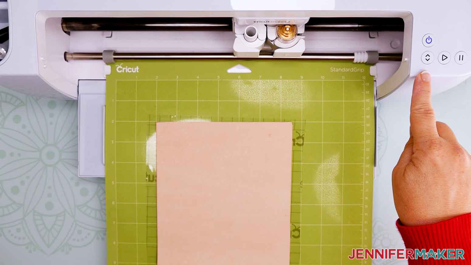 Pressing the arrows to load leather into Cricut machine.