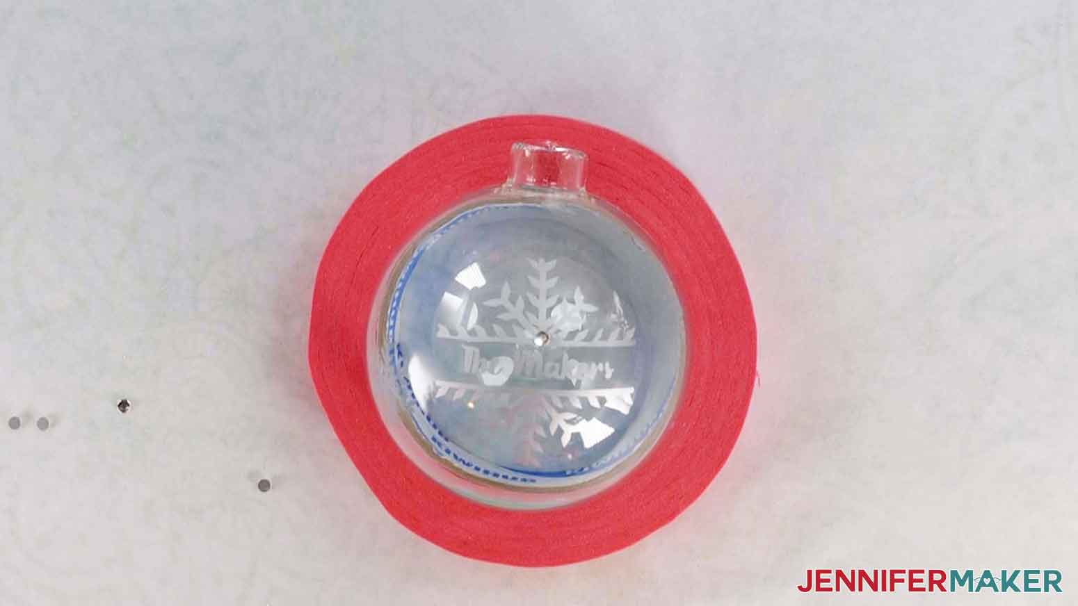 Etched glass ornament inside painter's tape roll with crystals applied to its surface