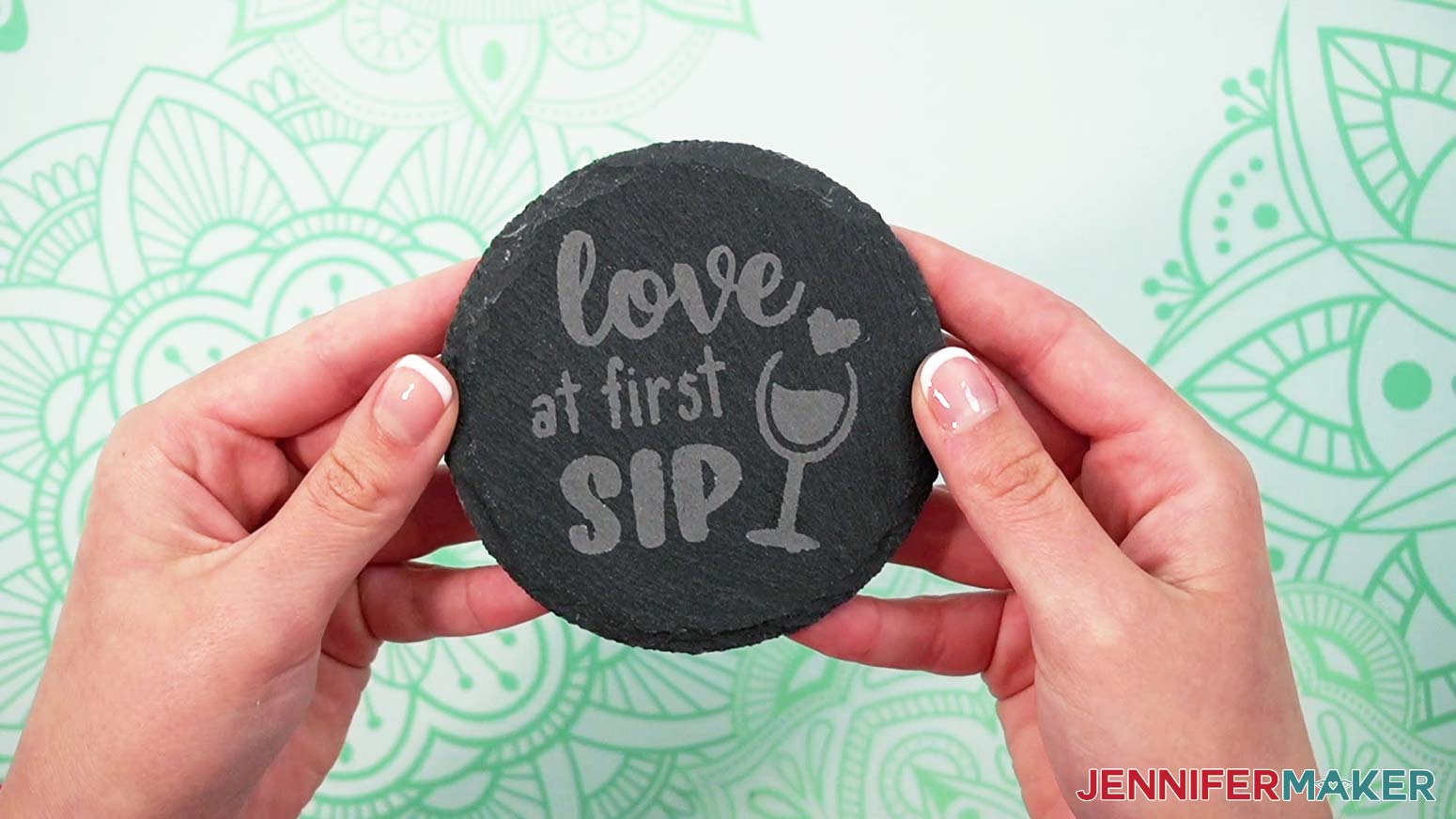 A finished etched slate wine coaster with the words "love at first sip" and a wine glass graphic.