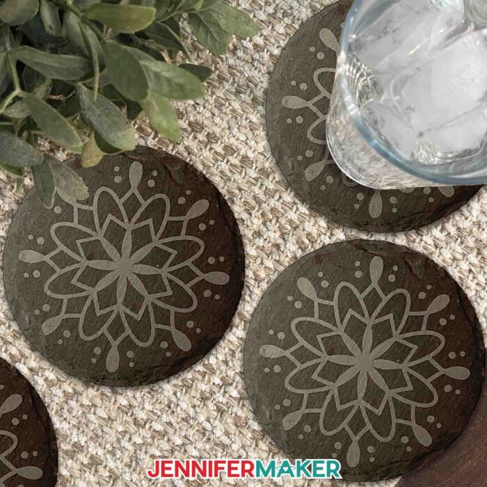Learn how to etch slate with JenniferMaker's tutorial! Make an etched slate cheeseboard and coasters. Image shows four dark gray slate coasters etched with light gray mandala designs.