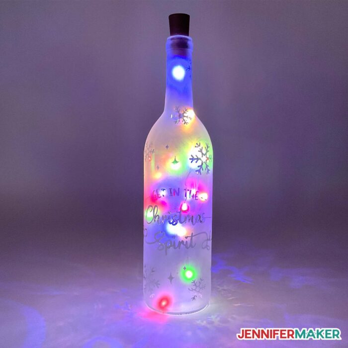 An etched wine bottle with multicolored lights.