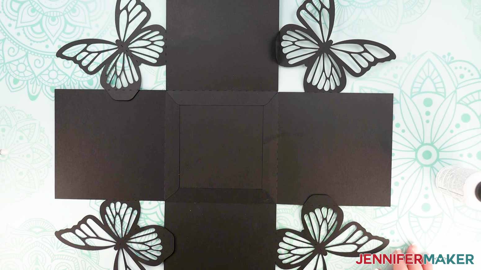 The five black cut pieces for the larger sized exploding butterfly box lying flat on a work surface with flaps correctly positioned.