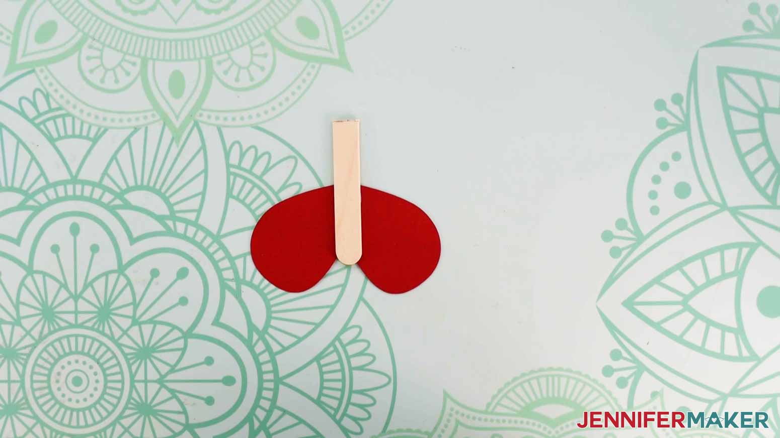 A photo of the bottom part of a magic butterfly for the exploding butterfly box showing a cut popsicle stick with a red wing piece attached to the back.