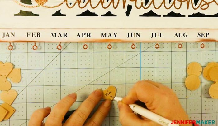 Writing a name and number on a date marker to make a family celebration and birthday board