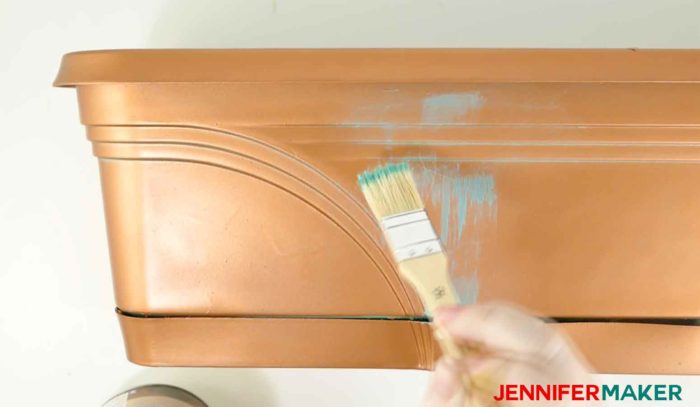 Brush on metallic paint to make a faux copper patina paint on an old plastic planter