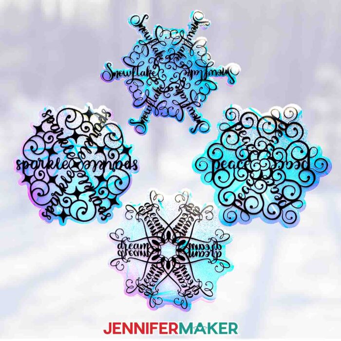 A window from inside the studio at Maker Farm look out onto a snowy landscape -- the windows are decorated with four snowflake-shaped window clings with stylized word art from the Festive Snowflake Designs tutorial