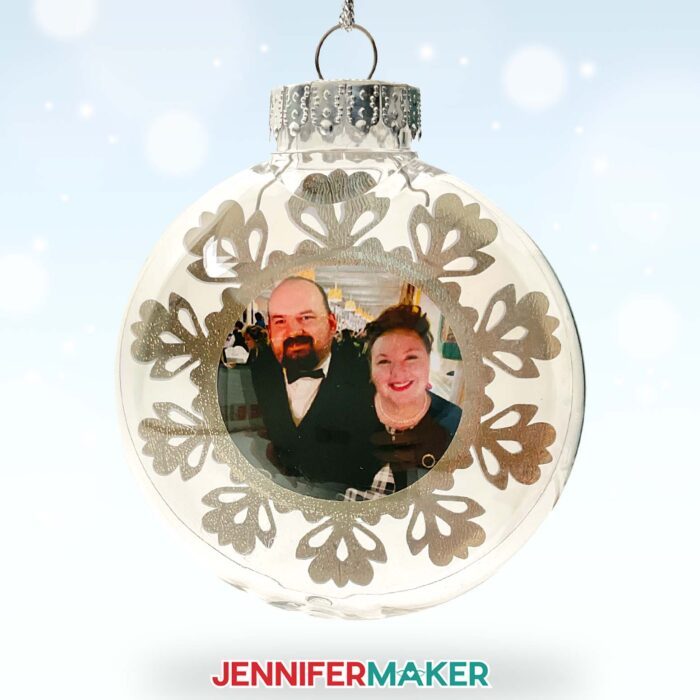 How to make a beautiful floating ornament! Plus, size your inserts perfectly with my floating ornament size chart. A floating ornament sits on a stand, filled with a printable vinyl photo of Jennifer and Greg at a black-tie event, with a silver foil snowflake frame around them. Make Cricut Christmas Ornaments with JenniferMaker's tutorial!