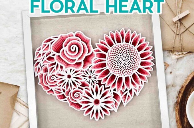 Cut paper floral heart in reds and white framed on a white shadow box.