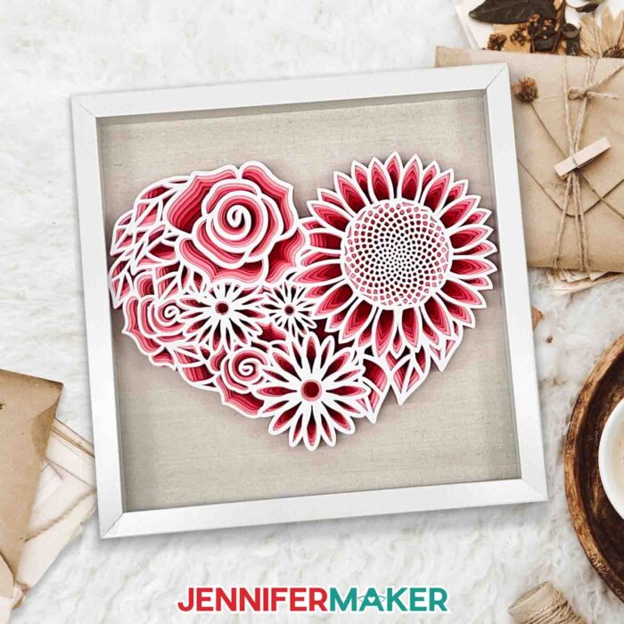 White framed layered cardstock project in shades of red and white made using a Cricut and a floral heart SVG.