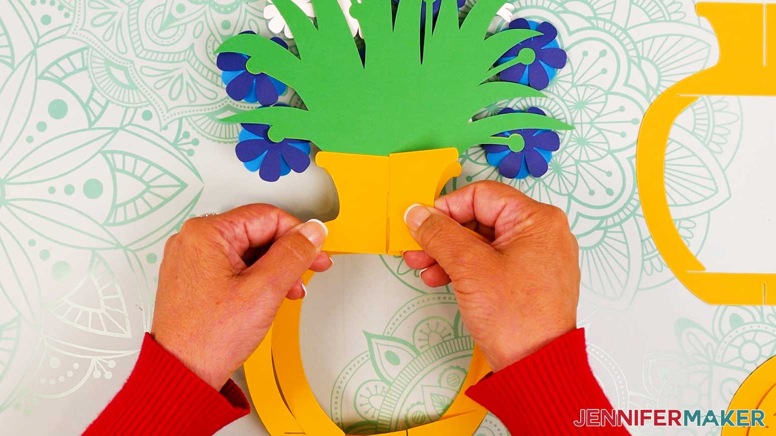 Take the vase frame piece with slits at the top and bottom of the neck and slot it inside the main vase frame.
