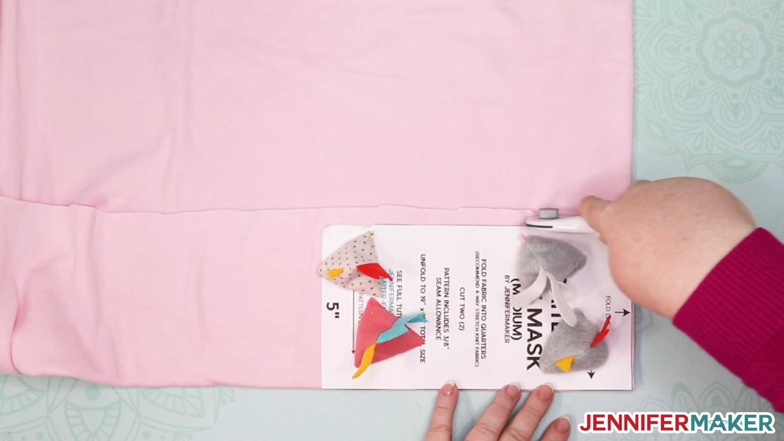 Cutting pink knit fabric with a rotary cutter to make a DIY gaiter face mask