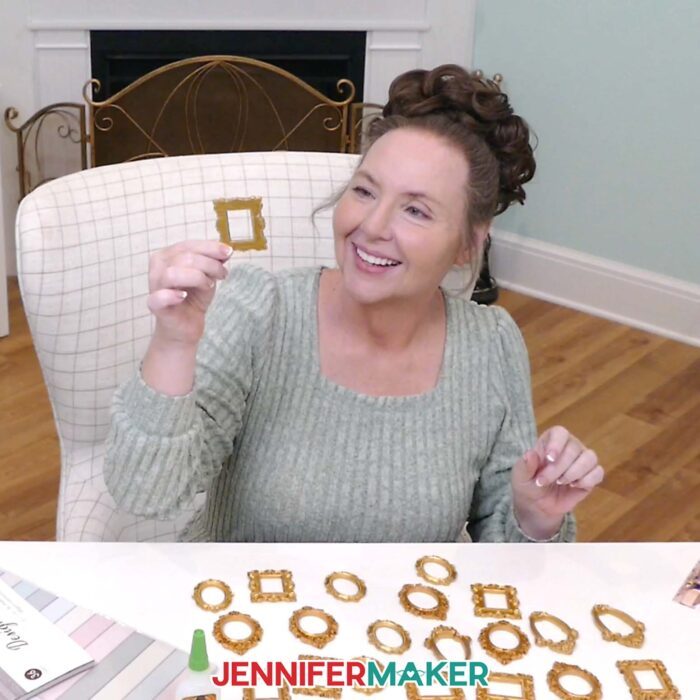 Jennifer holds up a mini craft frame to examine it, with an assortment of other frames on her desk