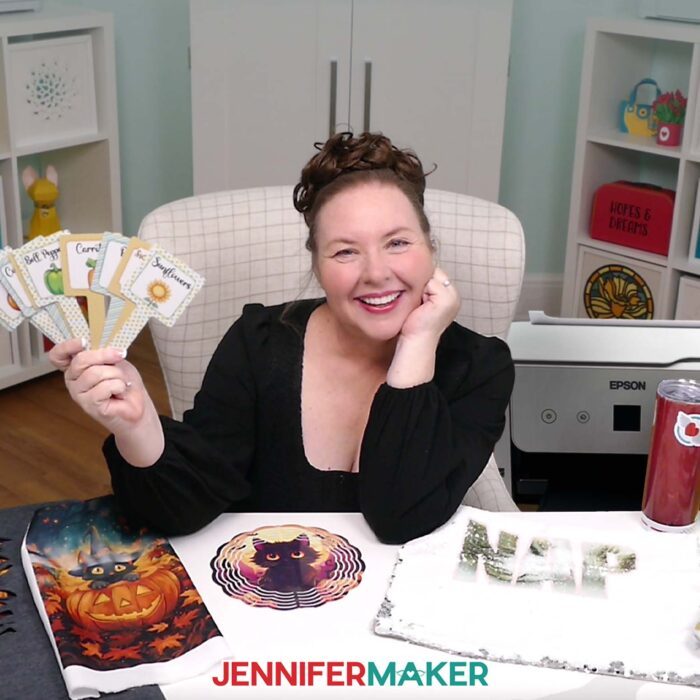 Jennifer shows some faded sublimation projects while holding up a set of  perfectly sublimated garden stakes.