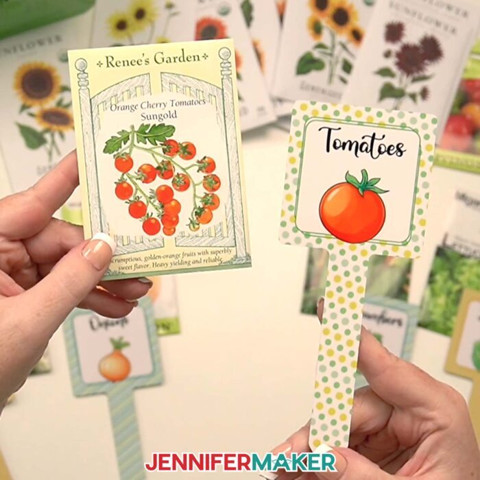 Jennifer holds up a an Orange Cherry Tomatoes seed packet with a matching "Tomatoes" plant stake.